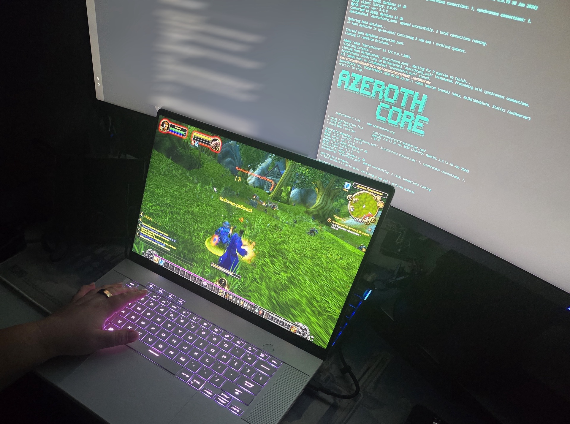 AzerothCore authserver console on the big screen, the game running on the laptop below